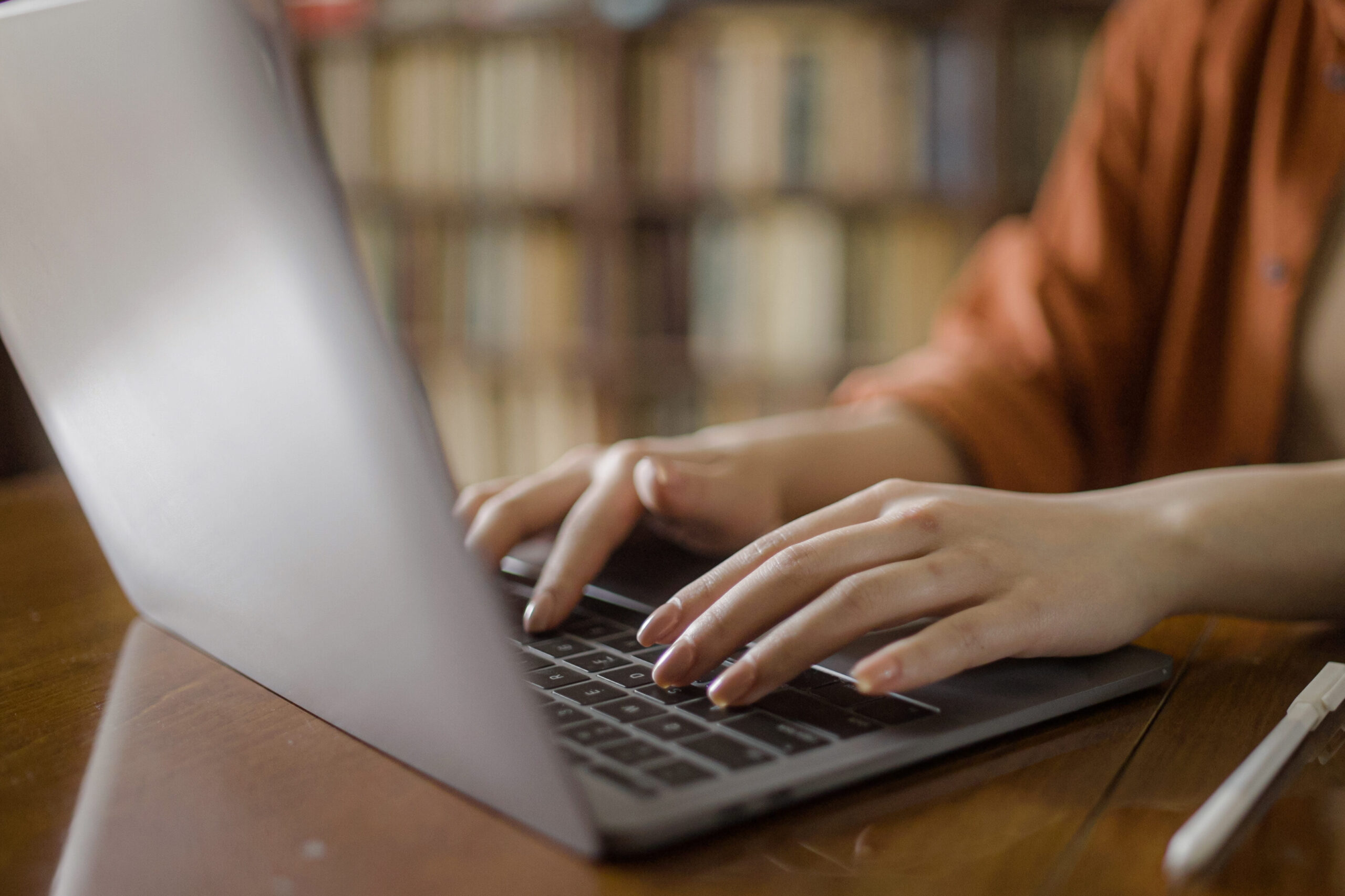 Woman typing on laptop, freelancer working at city library, hands close-up